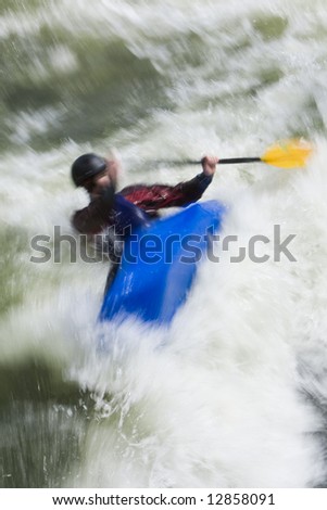 A slow shutter speed shot of a kayaker capsizing in very rough whitewater.