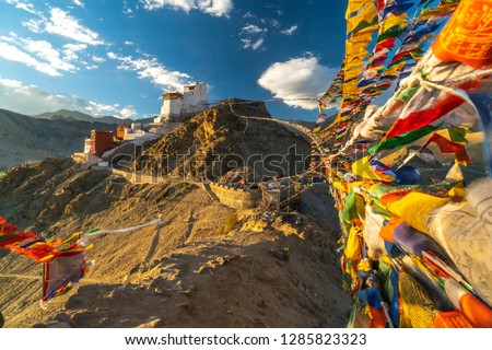 Buddhist Prayer flags connecting two peaks of Peak of Victory above Leh, India.  Monastery on the top of the hill. Royalty-Free Stock Photo #1285823323