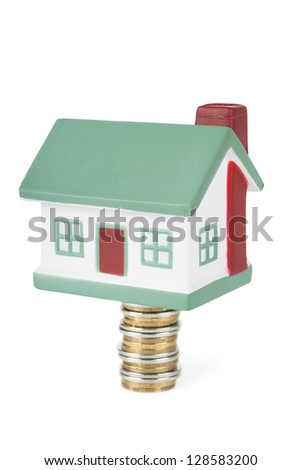 Little house toy on a stack of coins isolated over white background