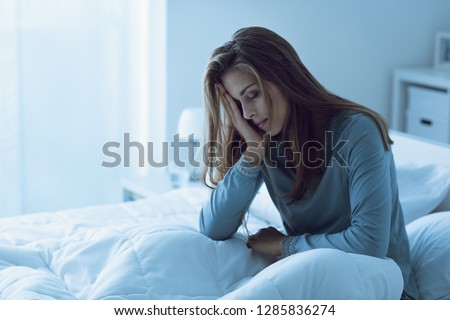 Depressed woman awake in the night, she is touching her forehead and suffering from insomnia Royalty-Free Stock Photo #1285836274