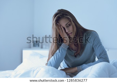 Depressed woman awake in the night, she is touching her forehead and suffering from insomnia Royalty-Free Stock Photo #1285836277