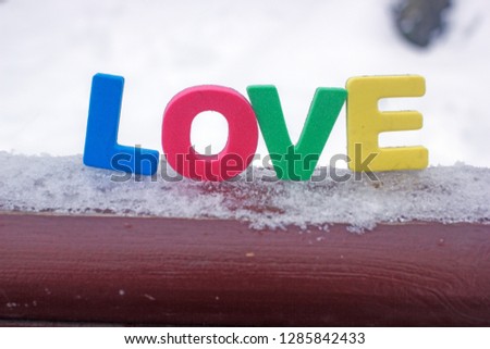 The word love in multicolored letters on white snow, a background about love, a background to the day of lovers, multi-colored letters, the word loveon white snow, a background about love, a backgr
