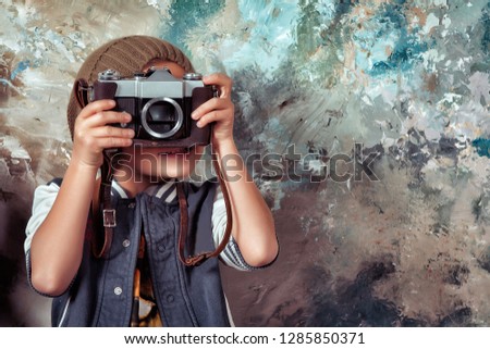 
child dreams of becoming a photographer. Portrait of a casual style boy with a retro camera in his hands. The boy smiles happily