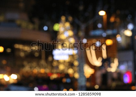 Blurred light bulbs around city in night time. Defocused bokeh decorating during festival. Christmas and New Year celebration moment.