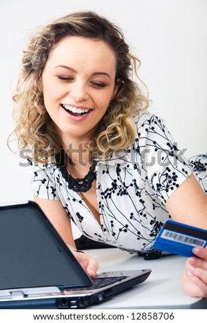 Photo of pretty girl typing on the keyboard of laptop and holding credit card in hand