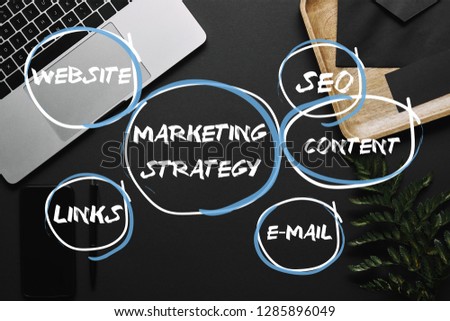 Smartphone and laptop on black background with marketing strategy, seo, content, e-mail, links and website icons 