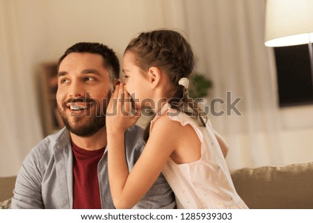 family, fatherhood, leisure and people concept - happy daughter whispering secret to father at home