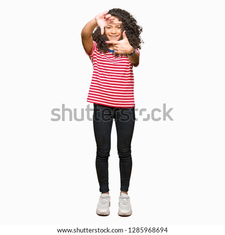 Young beautiful woman with curly hair wearing stripes t-shirt smiling making frame with hands and fingers with happy face. Creativity and photography concept.