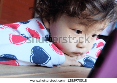 Cute asian little girl lying watching smart phone.