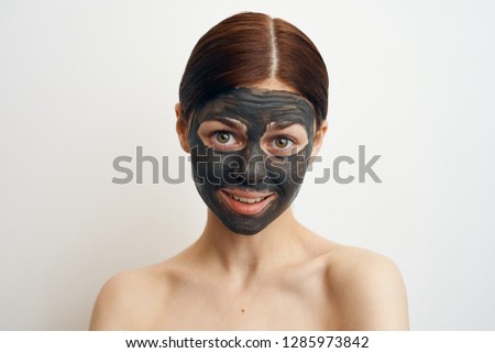 young woman in clay mask on a light background portrait