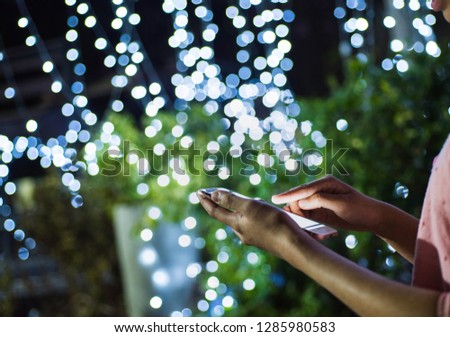 Close-up image of male hands using smartphone at night on city shopping street, searching or social networks concept, hipster man typing an sms message to his friends
