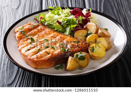 Grill steak swordfish served baby potato and fresh salad close-up on a plate on a black background. horizontal Royalty-Free Stock Photo #1286011510