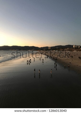Picture of the beach with people enjoying themselves during the sunset and reflections in the water