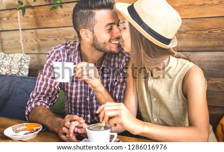 Young fashion lovers couple at beginning of love story - Handsome man kissing beautiful woman at coffee shop bar - Relationship concept with happy boyfriend and girlfriend together - Warm retro filter Royalty-Free Stock Photo #1286016976