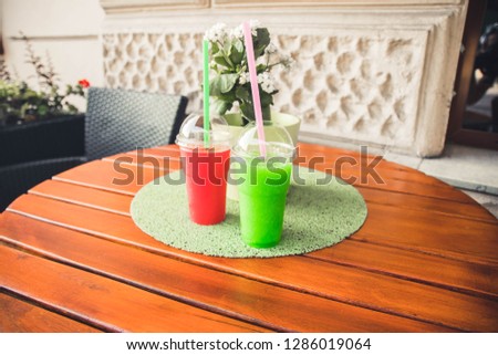 pink and green ice cream takeaway cocktail plastic glass on the wood table with copy-space for textures.