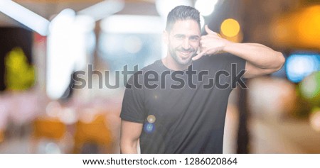 Young handsome man over isolated background smiling doing phone gesture with hand and fingers like talking on the telephone. Communicating concepts.
