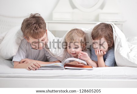 three boy read book indoors
