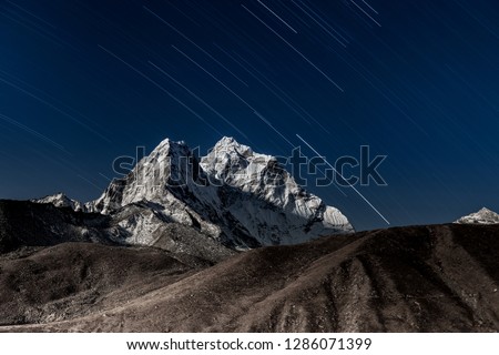 Stars falling above Ama Dablam mountain peak lit up by a bright moonlight. Bizarre photo.