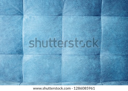 Close-up comfortable blue soft back of the sofa with curly stitching. Modern design