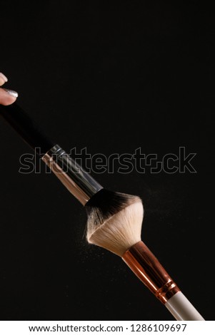 Make up cosmetic brushes with powder blush explosion on black background