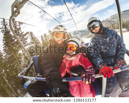 happy smiling family skiers on ski lift making selfie