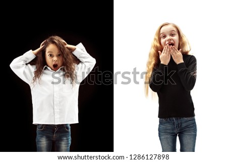 The portrait of two happy screaming girls on a white and black studio background. Human emotions concept. Comparison. The childhood, smile, happiness, joy, kid, friendship concept