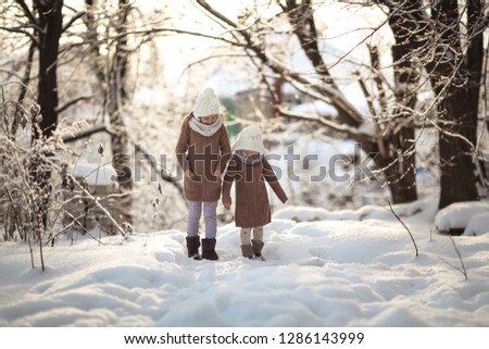 Happy childhood. Sisters, children in sweaters and sharks playing outside, winter and a lot of snow. Scandinavian style.