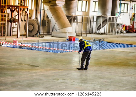 Worker stretching the red white warning tape to the pole at construction site.Red and white Hazardous restricted area tape at construction area of factory to mark territory works. Royalty-Free Stock Photo #1286145223