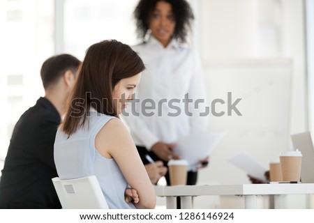Diverse businesspeople in office during briefing focus on female worker feels guilty unhappy offended and frustrated having problem or disrespect from colleagues or made mistake, listens boss scolding Royalty-Free Stock Photo #1286146924