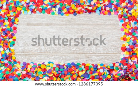 Background for carnival, New Year - colorful, round confetti as a frame on wood