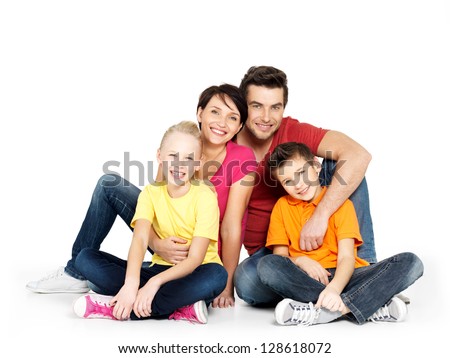Portrait of the happy  family with two children sitting at studio on white floor