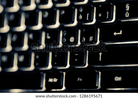 Backlit desk computer keyboard, monochrome interpretation of the shot.