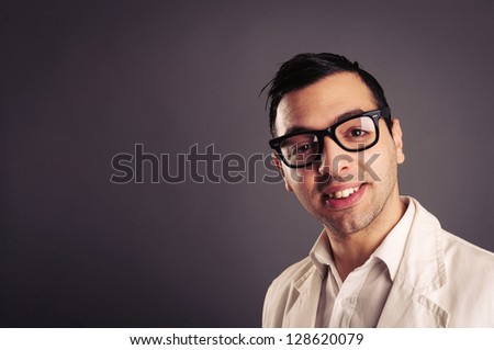 Funny portrait of young nerd with eyeglasses on grey background.
