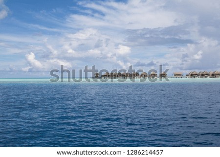 Luxury bungalows of a hotel on a shallow reef crest on a Maldives island 