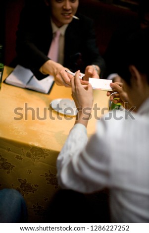 Hand holding a business card and a cigarette.