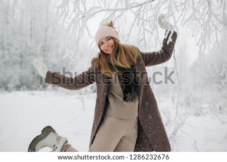 Picture of happy blonde woman in hat on walk in winter forest