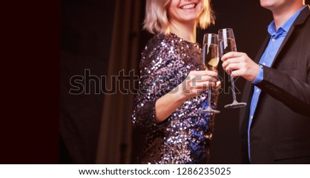 Picture of woman in brilliant dress and men with wine glasses with champagne on black background