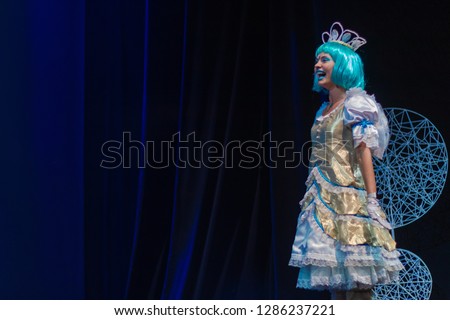 Actress in princess costume plays a performance for children on the theater stage