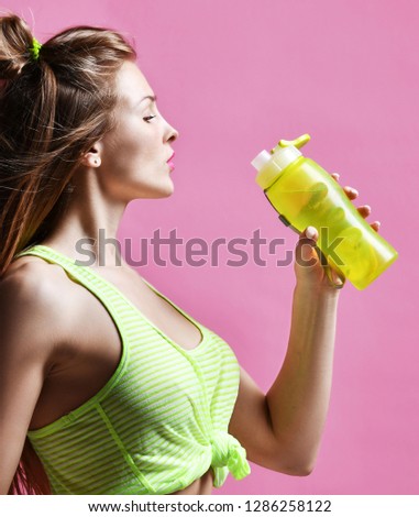 Young sport woman hold drinking water sport bottle on pink background