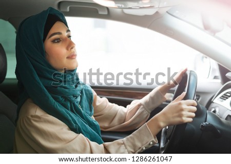 Arabian businesswoman wearing hijab driving her car.