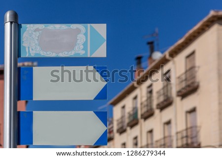 Classic style posters hanging on a metal pole with some buildings in the background, on a sunny day