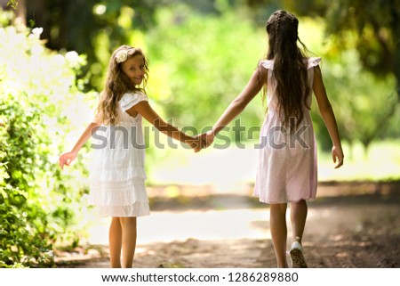 Two young girls walk down a quiet country road.