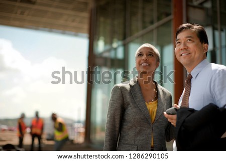 Two smiling businesspeople discuss future plans at a construction site .
