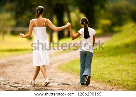 Teenage girl walking hand in hand with her younger sister.