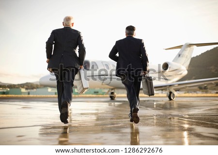 Two businessmen running towards a private jet
