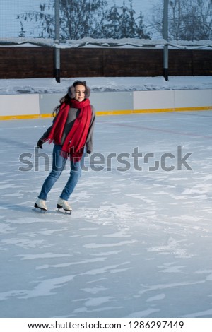 beautiful woman is having winter fun activity  skating in the evening ice rink. Sporty girl