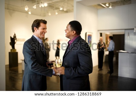 Business colleagues attend an art gallery opening.
