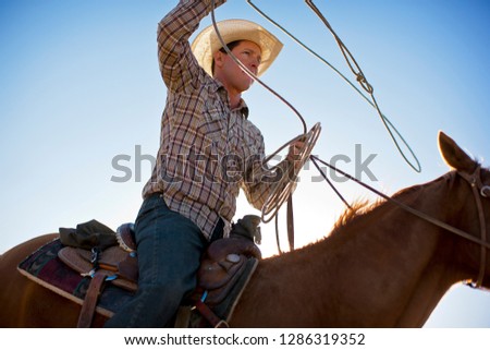 Rancher holding a lasso while riding a horse.