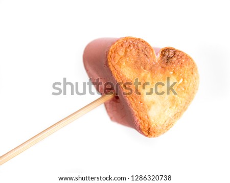 roasted heart form marshmallows on a skewer in female hand on white background