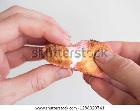 Roasted marshmallows in female hand on white background. Man breaks roasted marshmallows in hands. What is inside the roasted marshmallow